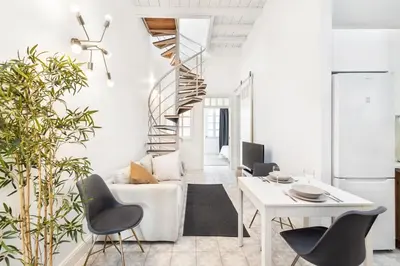 a living room with a staircase and a table and chairs at RG Casa do Carmo in Faro