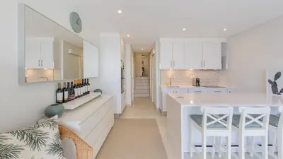 a white kitchen with white cabinets and a white island at Keiko in Vale do Lobo