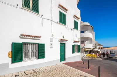 a street with white buildings with green shutters at Private 2 Bed Apartment in Albufeira Old Town in Albufeira