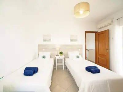 two beds in a room with white walls and blue pillows at Villa Inês by Interhome in Galé
