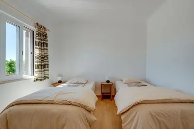 two beds in a white room with a window at Quinta Coelho in Guia