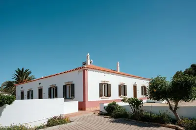 a white and pink building with a tree in front of it at Quinta Coelho in Guia