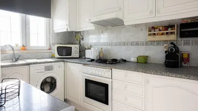 a kitchen with white cabinets and a stove top oven at Casa da Praia - São Rafael - BY BEDZY in Albufeira