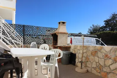 a patio with a white table and chairs and a stone wall at Casa da Praia - São Rafael - BY BEDZY in Albufeira