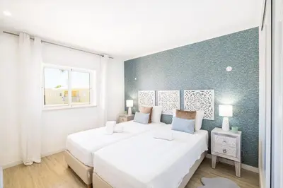 a white bedroom with two beds and a window at Benjamin Apartment in Guia