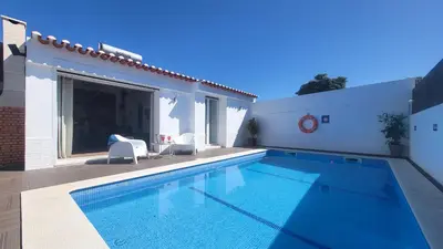 a swimming pool with two chairs next to a house at Oura Villa V2 Jacarandá in Albufeira