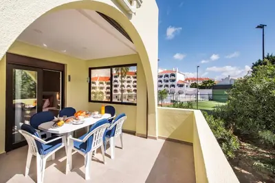 a dining room with a table and chairs on a balcony at Oura Sunset Apartement in Albufeira