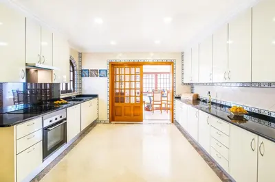 a large kitchen with white cabinets and a wooden door at Villa Molucas by Algarve Vacation in Albufeira