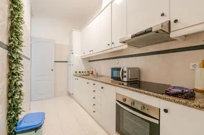 a kitchen with white cabinets and a blue stool at Down Town Beach House in Albufeira