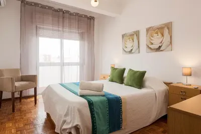 a bedroom with a bed with green pillows and a window at OLIVE - Quarteira in Quarteira