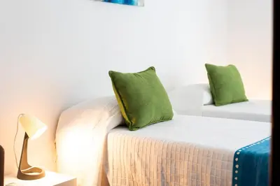 a room with a bed with a green pillow on it at OLIVE - Quarteira in Quarteira
