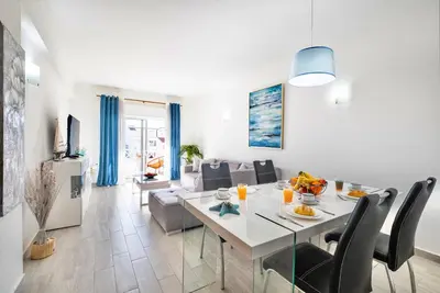 a dining room and living room with a table and chairs at Beautifull CentralApart W/pool in Albufeira