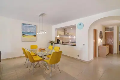 a dining room with a glass table and yellow chairs at Villa Nicola in Vale do Lobo