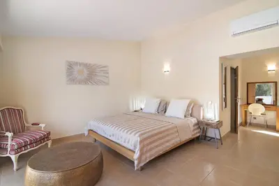 a bedroom with a large bed and a chair at Villa Nicola in Vale do Lobo