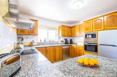 a kitchen with wooden cabinets and a bowl of oranges on the counter at Villa Estrelícia - Pool - Free wi-fi - New in Booking in Loulé