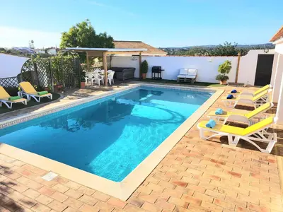a swimming pool with chairs and a house at Villa Estrelícia - Pool - Free wi-fi - New in Booking in Loulé