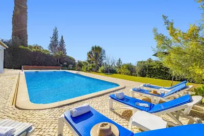a swimming pool with blue and white lounge chairs next to it at Villa Casa do Amendoal by Villa Plus in Albufeira