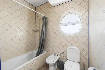 a bathroom with a toilet and a tub and a window at Villa Casa Morim by Villa Plus in Olhos de Água