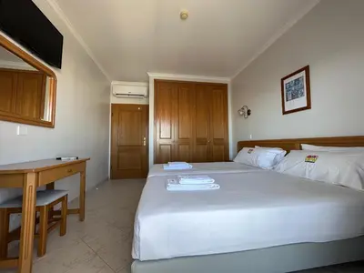 a bedroom with a large white bed and a desk at Sunset Haven in Albufeira - Short walk to Oldtown in Albufeira