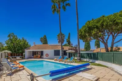 a swimming pool with chairs and a house at Villa Damasco by Villa Plus in Albufeira