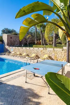 a ping pong table and chairs next to a pool at Villa V4 Máximo in Albufeira