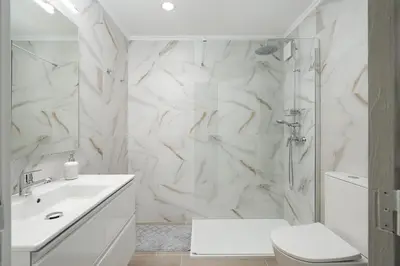 a white bathroom with a shower and a toilet at Apartamento Algarve, located center of Vilamoura in Quarteira