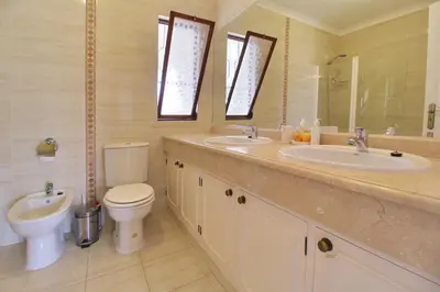 a bathroom with two sinks and a toilet and a mirror at Casa Francisco : Family Villa with private pool. Near to beach in Albufeira