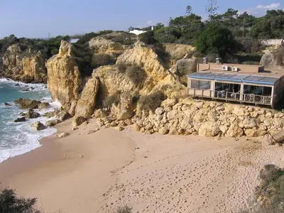 a beach with a building on a rocky cliff at Casa Francisco : Family Villa with private pool. Near to beach in Albufeira