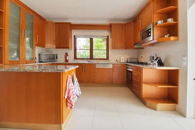 a kitchen with wooden cabinets and a counter top at Casa Francisco : Family Villa with private pool. Near to beach in Albufeira