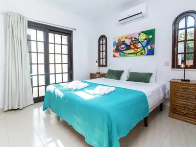 a bedroom with a bed and a painting on the wall at Villa Dogueno by Stay ici Algarve Holiday Rental in Albufeira