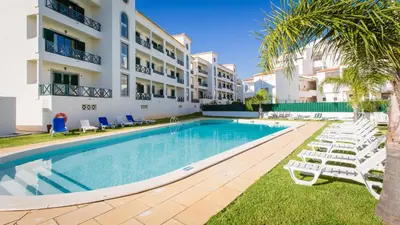 a swimming pool in front of a building with lounge chairs at Central Albufeira 2-B Apt Sleeps 6 Pool Parking in Areias Sao Joao
