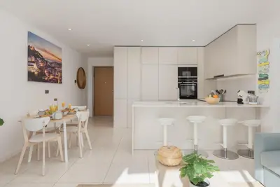 a kitchen and living room with white cabinets and a table at Terraços de Quarteira Green by Real Properties in Quarteira