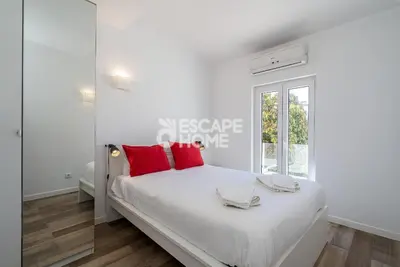 a white bedroom with a large bed with red pillows at Marina Village in Vilamoura