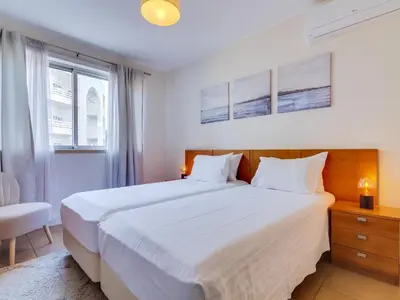 a bedroom with a large white bed and a chair at AL - Apartamento Carteia in Quarteira