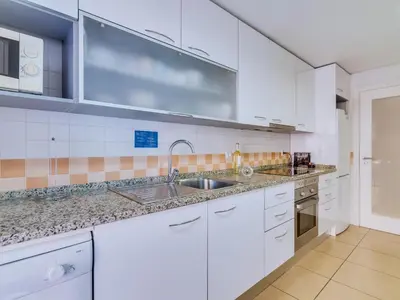 a kitchen with white cabinets and a sink at AL - Apartamento Carteia in Quarteira