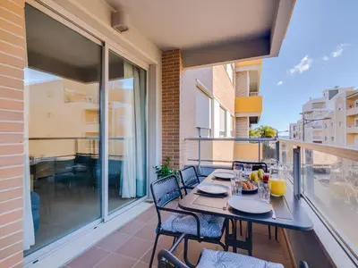 a patio with a table and chairs on a balcony at AL - Apartamento Carteia in Quarteira