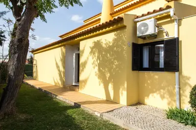 a yellow house with a tree in front of it at Oura 7 in Albufeira