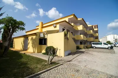 a yellow building with a car parked in front of it at Oura 7 in Albufeira