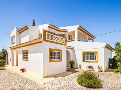 a white house with yellow accents at Vila Montejunto in Albufeira