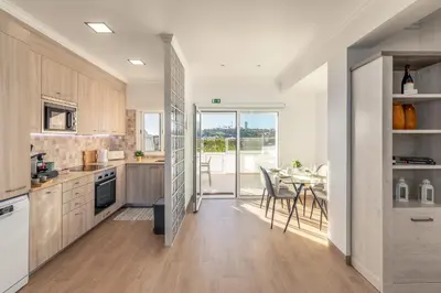 a living room with a gray couch and a kitchen at Apartamento Sunset on the Sea in Albufeira