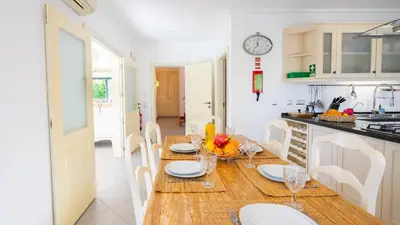 a kitchen with a table and chairs and a clock on the wall at Ocean View Villa in Boliqueime