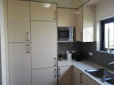 a kitchen with white cabinets and a sink and a microwave at Spacieux Appartement Logis des Fées de la Marina en rez-de-chaussée de chaussée in Albufeira