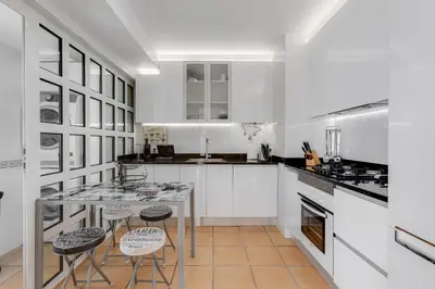 a kitchen with white cabinets and a table and stools at VILASOL - 