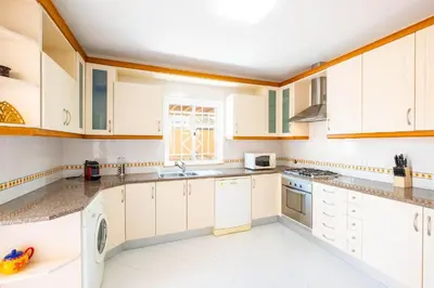 a kitchen with white cabinets and a window at Villa Habitate - pool fence & heating beach bars in Albufeira