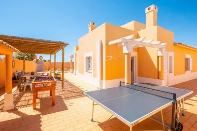 a ping pong table on the patio of a house at Villa Habitate - pool fence & heating beach bars in Albufeira