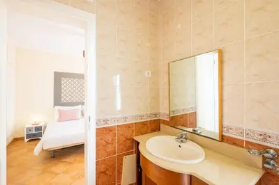 a bathroom with a sink and a mirror and a bed at Villa Habitate - pool fence & heating beach bars in Albufeira