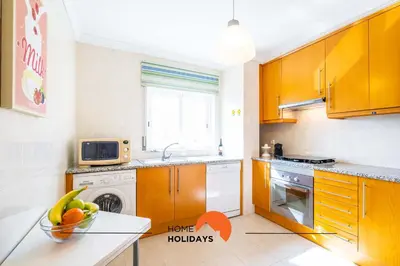 a kitchen with wooden cabinets and a bowl of fruit on a counter at #115 Bernardo Flat by Home Holidays in Albufeira