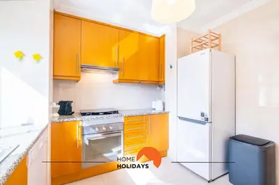a kitchen with yellow cabinets and a refrigerator at #115 Bernardo Flat by Home Holidays in Albufeira