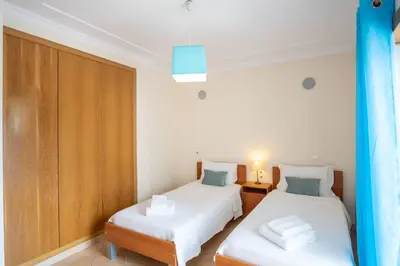 a bedroom with two beds and a wooden cabinet at Apartment Hugo - Complex perfect for families in Albufeira