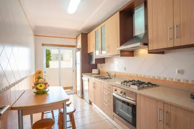 a kitchen with wooden cabinets and a small table in it at Apartment Hugo - Complex perfect for families in Albufeira